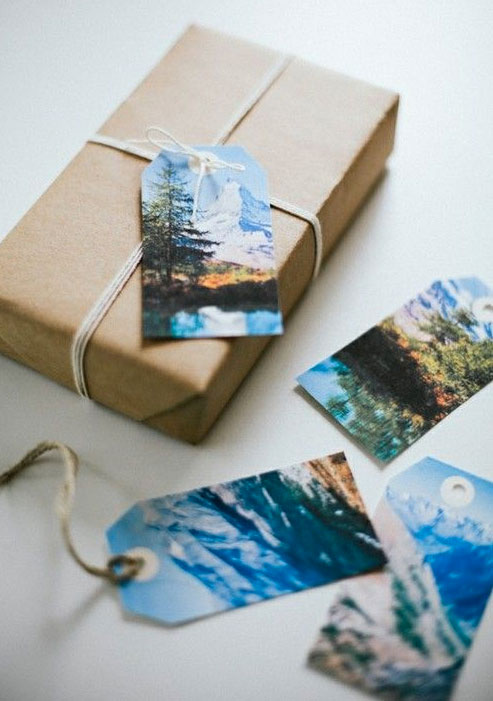 4 homemade gift tags made from scenery photos attached to brown paper wrapped gift and twine