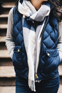 torso shot of a woman wearing layers and a blue puffy vest