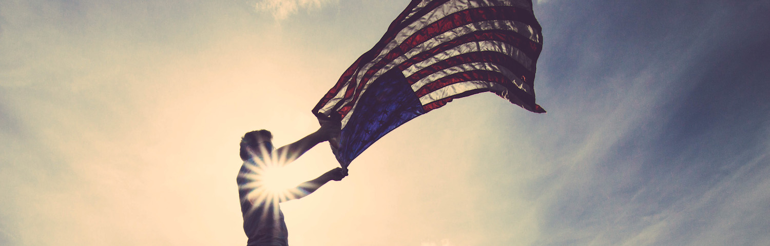 american flag being held by a man's silhouette
