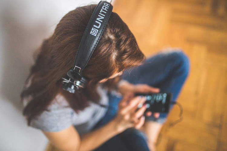 girl sitting cross-legged listening to music with headphones