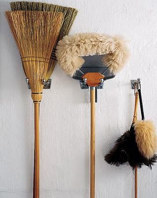 3 old fashioned brooms hung on the wall