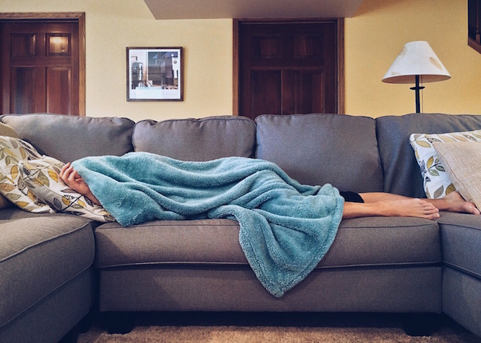 man sleeping under blanket on couch
