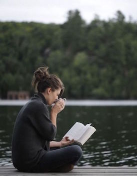 woman reading on the dock at the lake