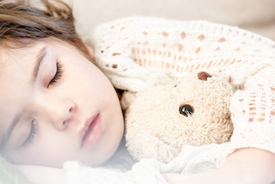 young sleeping girl snuggling teddy bear