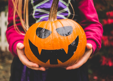 kids crafted jack-o-lantern held by girl in costume