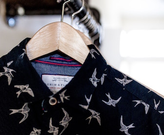 black shirt with sparrows hanging on hanger in closet
