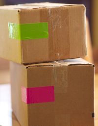 two stacked cardboard boxes with colored tape pink and green