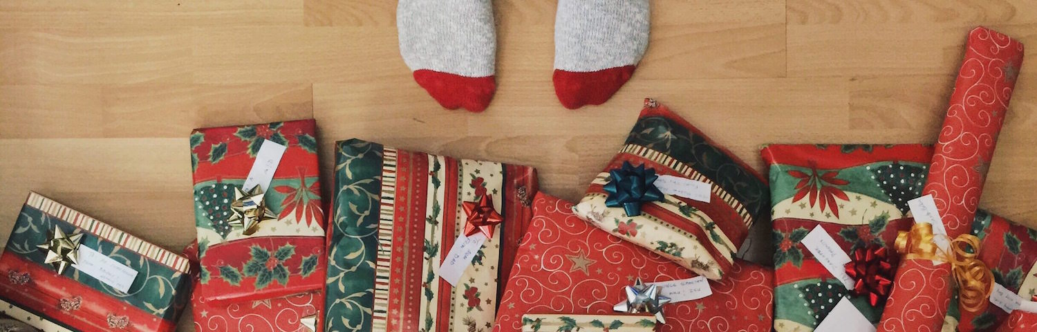 aerial view of toes in socks in front of a pile of wrapped christmas presents