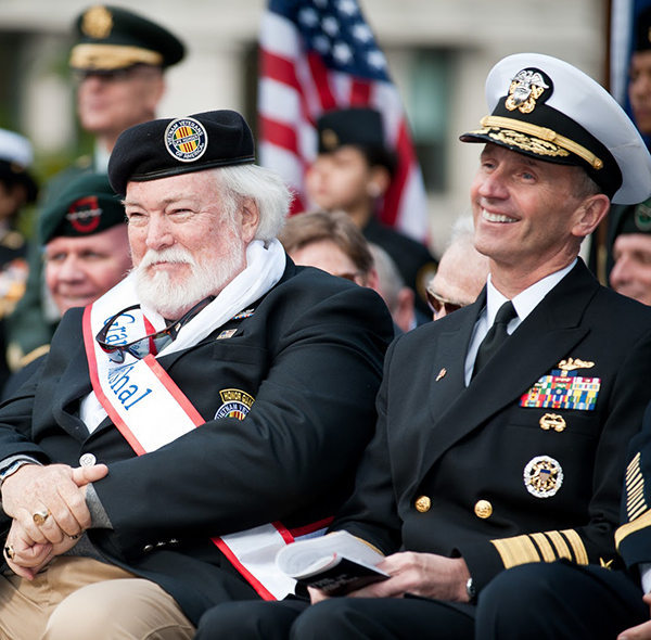 Two military veterans in uniform sitting smiling in ceremony