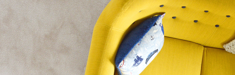 close up of arm of yellow couch with blue pillow