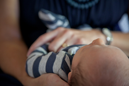 woman with baby in her lap in blue striped onesie