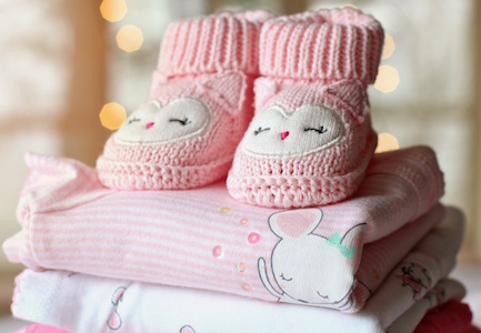 stack of baby girl pink clothes with sleeping owl face booties on top