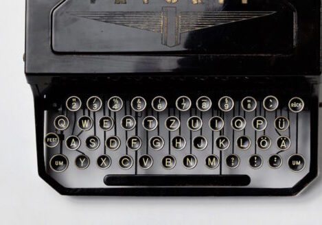 aerial view of old typewriter keyboard against white tabletop