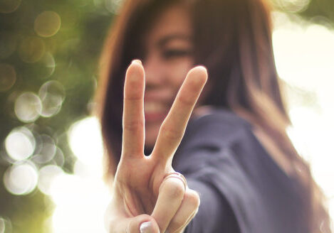 woman making peace sign towards camera and smiling
