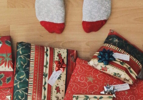 aerial view of toes in socks in front of a pile of wrapped christmas presents