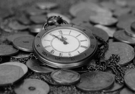 grayscale bed of coins with a open-face pocketwatch